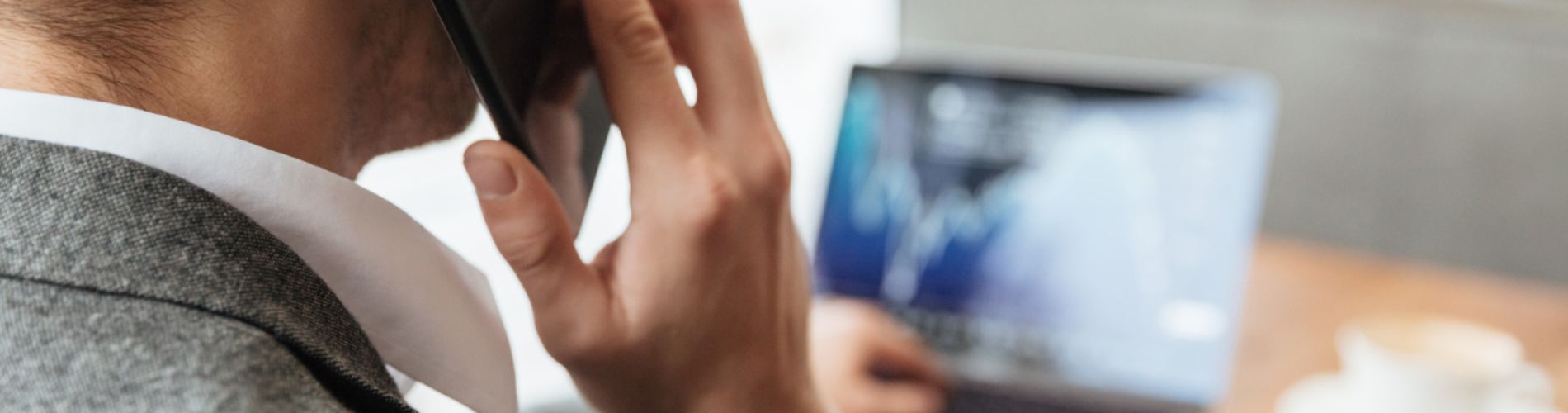 immagine-potata-dell-uomo-d-affari-che-si-siede-dalla-tavola-in-caffe-e-che-analizza-gli-indicatori-sul-computer-portatile-mentre-parlando-dallo-smartphone-concentrati-sull-uomo